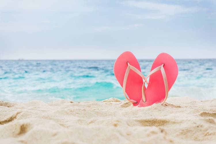 Pink flip flops standing up in the sand